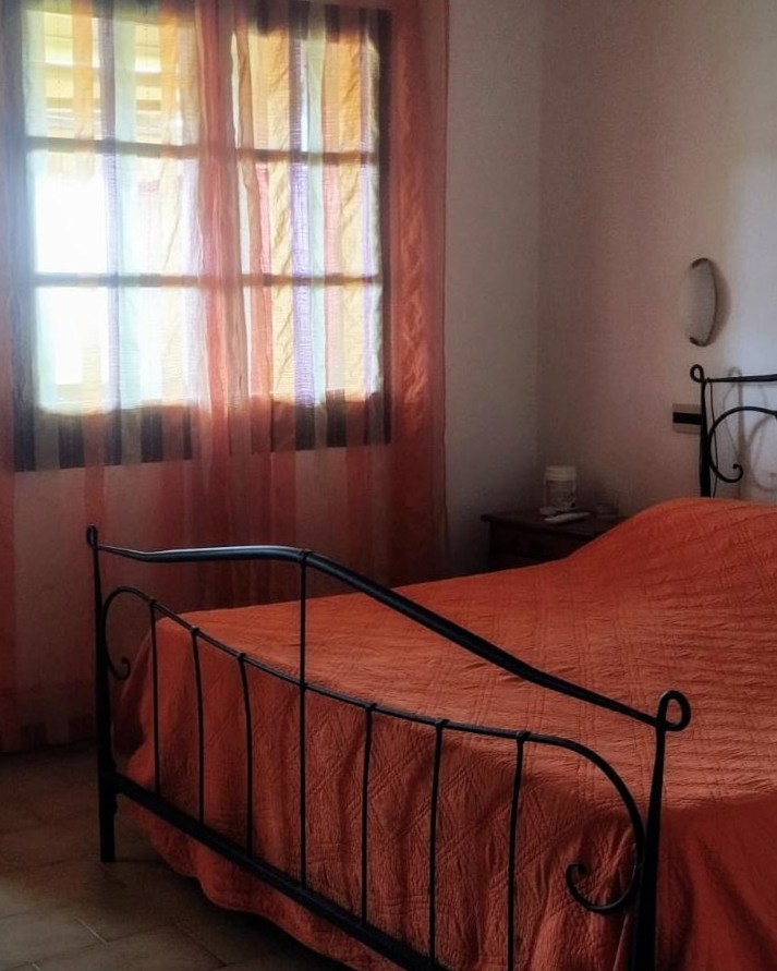 Camera matrimoniale arancione con letto in ferro battuto